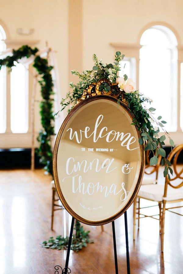 mirror wedding welcome sign decorated with greenery