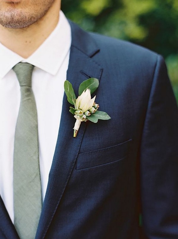 navy blue groom attire with green tie and boutonniere