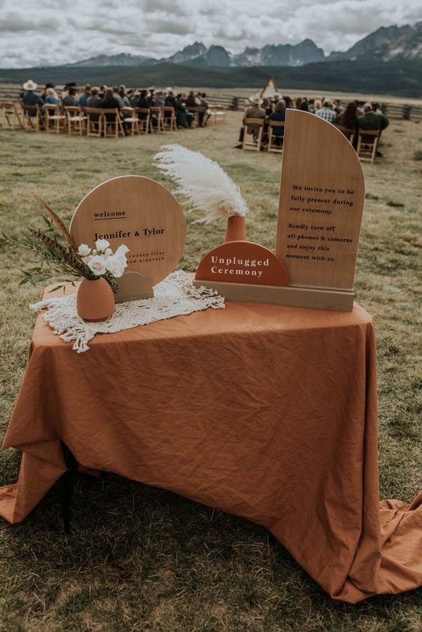 Using terracotta wedding welcome table signage in an open outdoor ceremony.