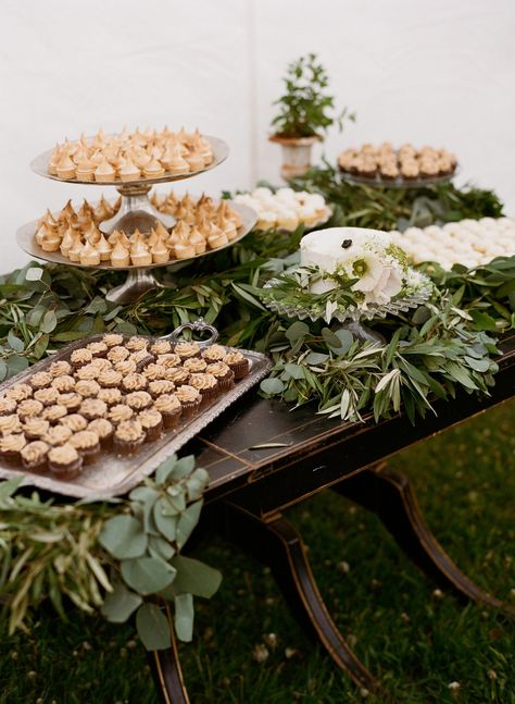 Wedding dessert bar with rustic cupcakes and lots of greenery 