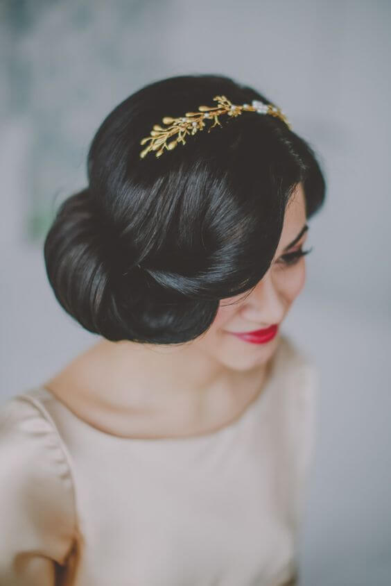 An updo with pin curls and a birdcage veil is a classic vintage-inspired wedding hairstyle for medium hair.