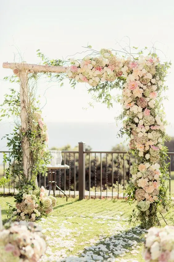 a lovely rustic wedding arch of branches with greenery twigs blush and white rustic blooms is idea for spring or summer