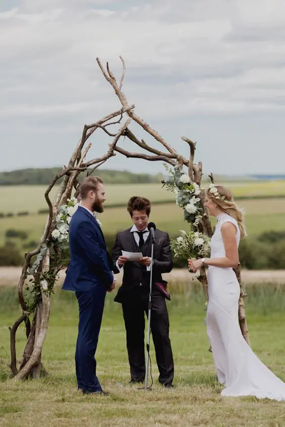 a rustic boho wedding arch of branches with with white blooms and greenery is a very simple idea to realize yourself