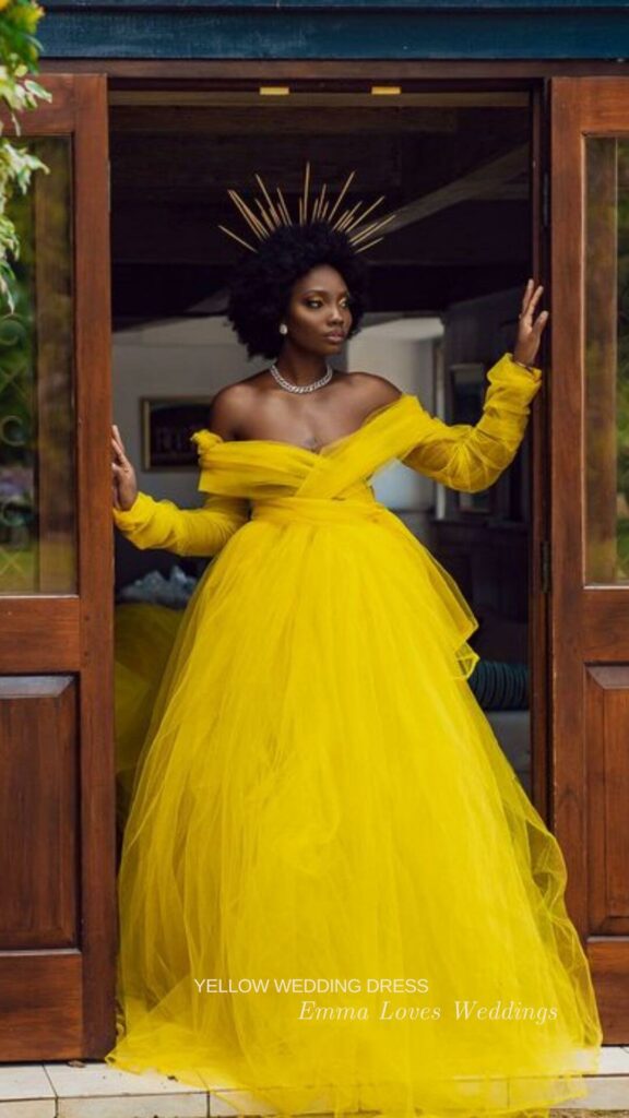 A dramatic idea for a royal look a yellow off the shoulder wedding ballgown with long sleeves layers of full skirt and a crown.