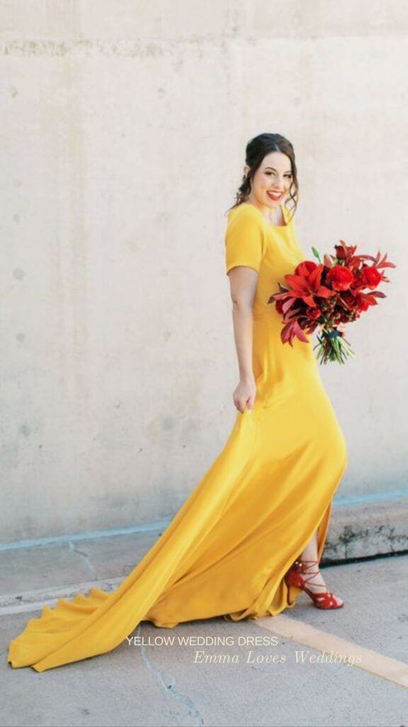 A minimalist yellow short sleeve wedding dress adorned with a red bouquet and matching red heels.