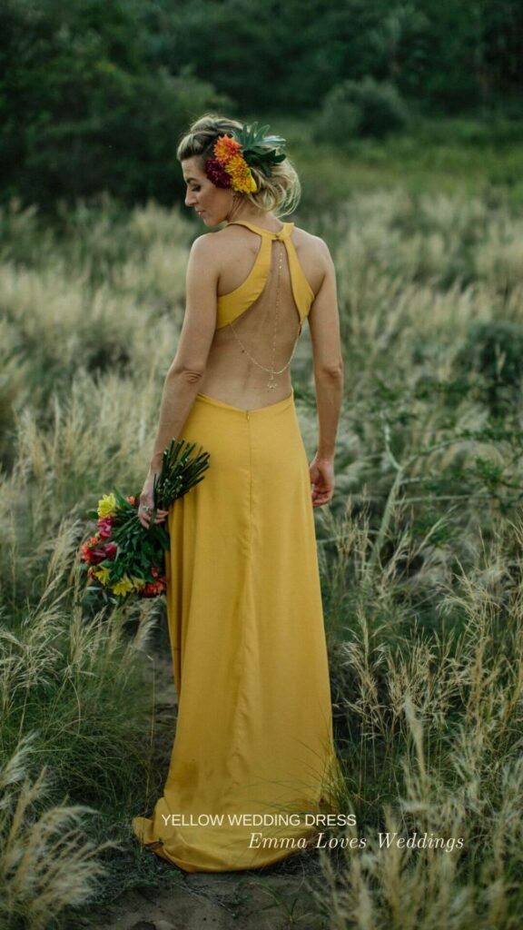 a mustard yellow open back wedding dress with colorful bouquet is a unique idea