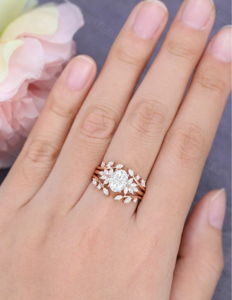 Rose gold and oval cut moissanite engagement ring with a marquise double curved diamond.