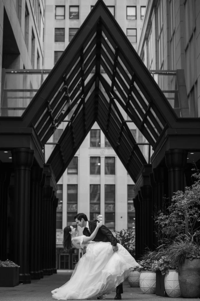 A stunning black and white picture of the couple set against a backdrop of textured buildings.