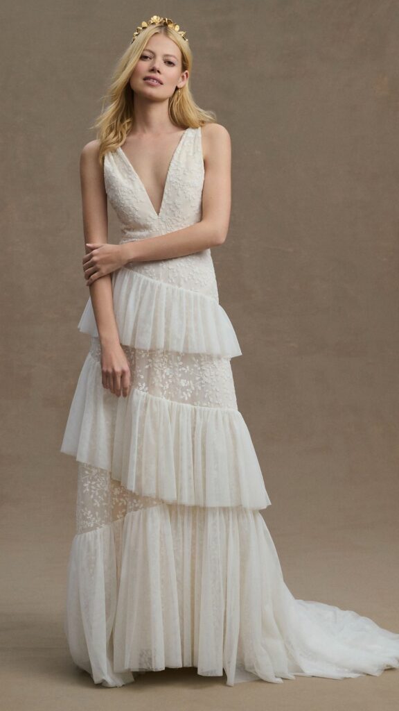 This delicately embroidered A line lace wedding dress with a plunging neckline and cascading ruffles exudes elegance.