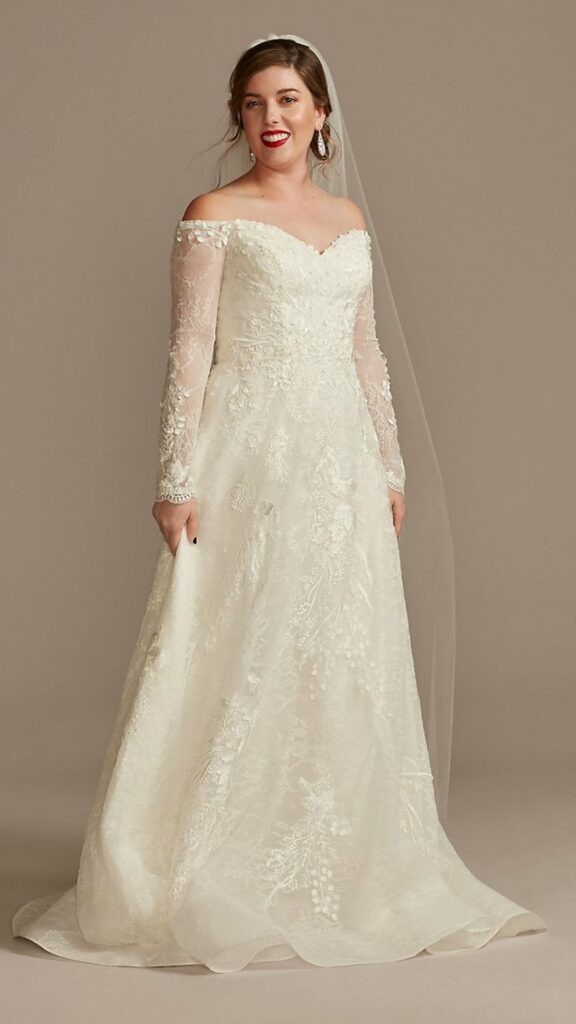 This off-the-shoulder A-line wedding dress is covered with leaf-patterned lace giving it depth and dimension.