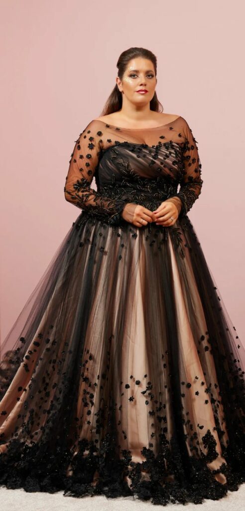 A stunning plus size black and gold wedding dress with a long sleeved mock sweetheart neckline and a full skirt.