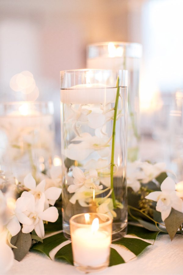 An elegant floating candle centerpiece featuring a mix of flowers set in a glass bowl of water creates the perfect beachy ambiance for a wedding.