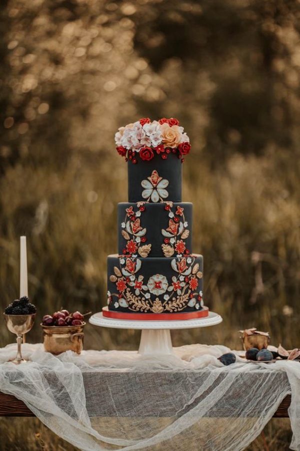 Black wedding cake decorated with sugar flowers and folk inspired designs