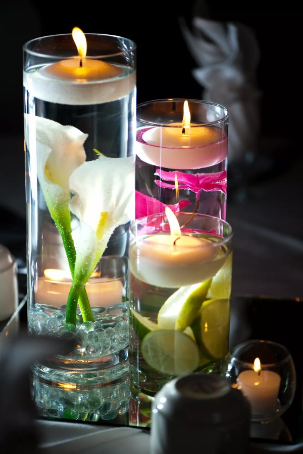 Calla lilies and other vivid flowers decorate glass vases with floating candles to create a warm and inviting wedding atmosphere