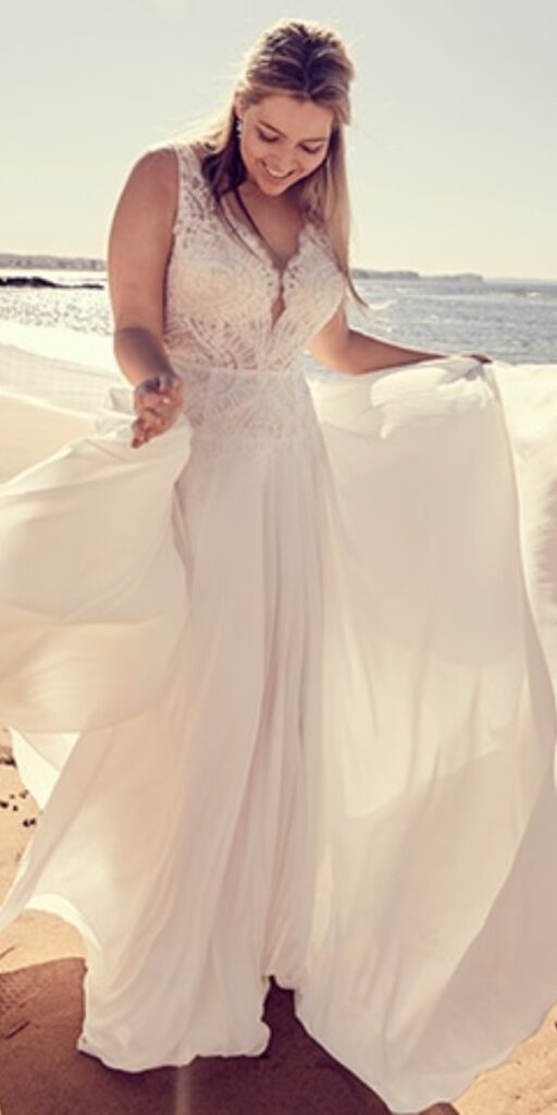 The long fitted bodice of this plus size beach wedding dress is adorned with vintage inspired pearl beading and it sits atop a flowy chiffon skirt.