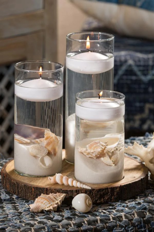 This beach themed wedding centerpiece features floating candles sand and seashells and is sure to be a show stopper at any reception.
