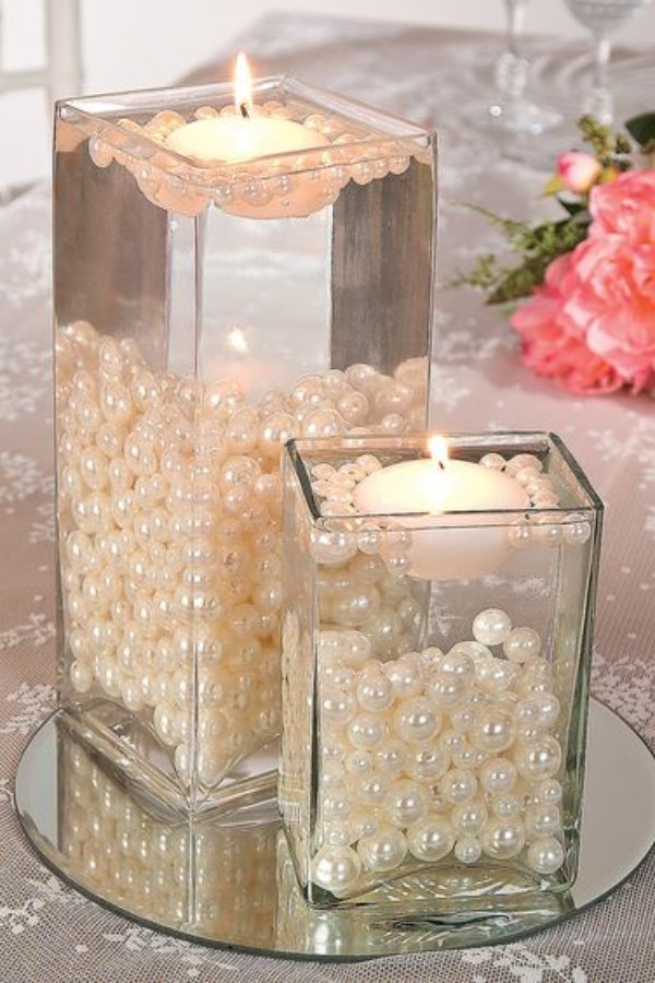 This magnificent white pearl floating candle centerpiece exudes purity and grace bringing the serene beauty of the ocean to your wedding celebration.