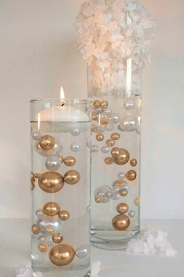 This trendy wedding centerpiece, a floating candle surrounded by gold and white pearls is sure to impress your guests.