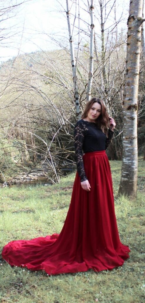 This two piece gothic lace red and black wedding dress with long sleeves features a long skirt with a train and is perfect for a fall outdoor wedding.