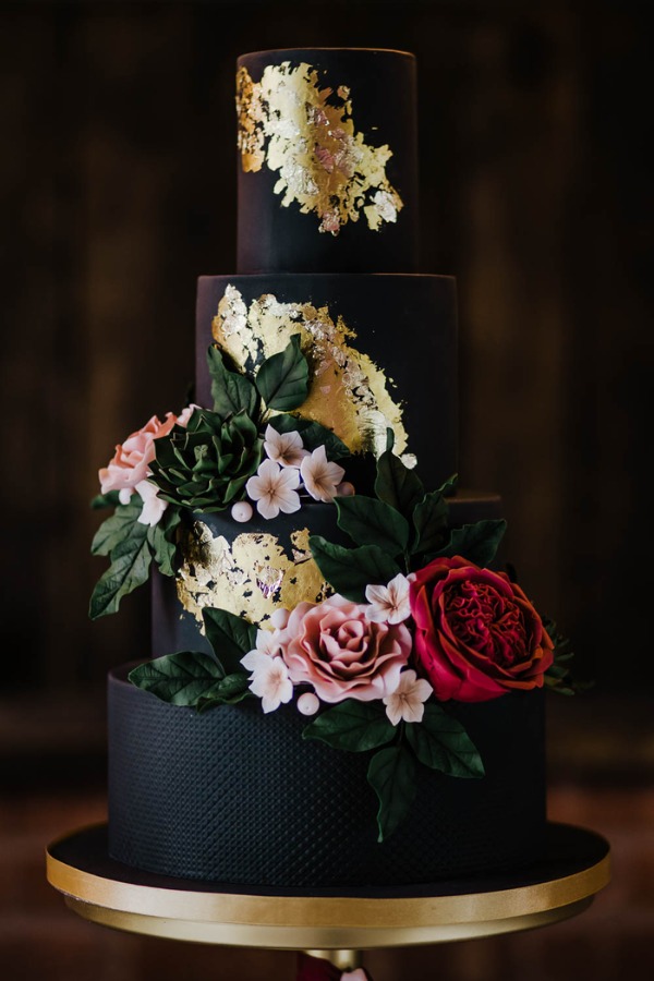 A black and bright florals wedding cake decorated with gold leaf accents