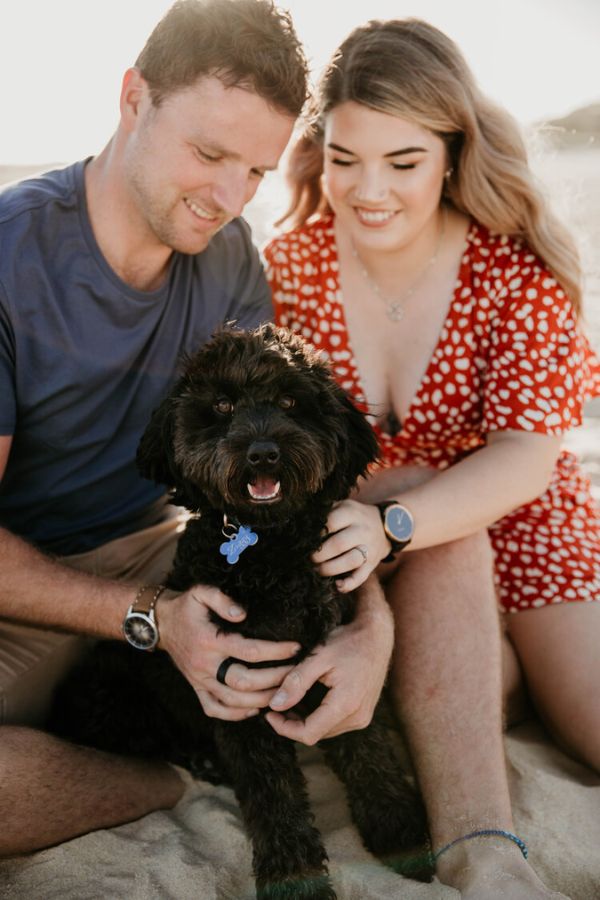 One adorable engagement photo idea is to pose with your pet friend on the beach