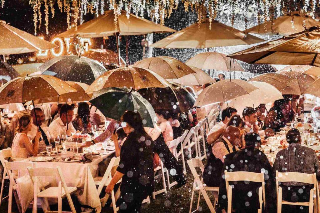 Guests dine gracefully under umbrellas in a setting that is a fascinating fusion of beauty and timeless artistry at the wedding reception