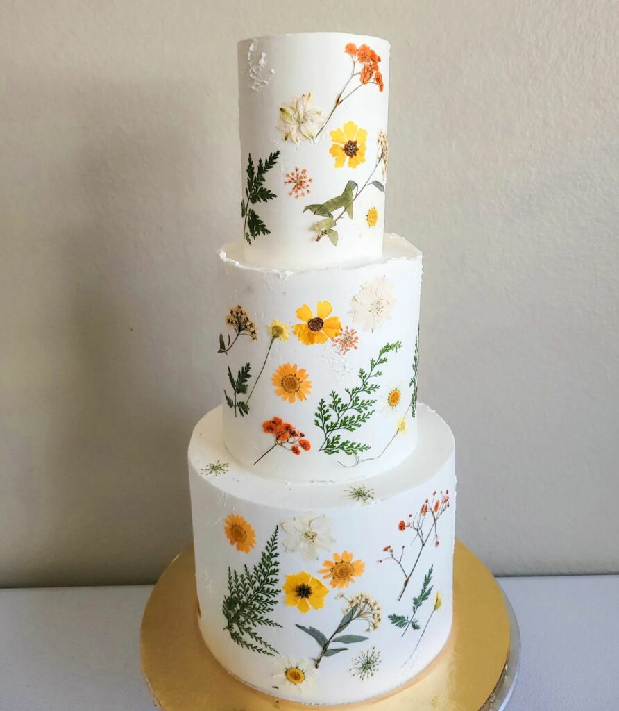 three tier sunflower wedding cake with pressed and wildflowers
