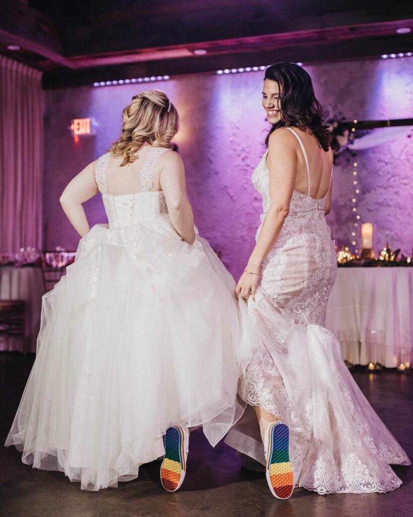 lesbian brides in a lace wedding dress and rainbow shoes to express their love story