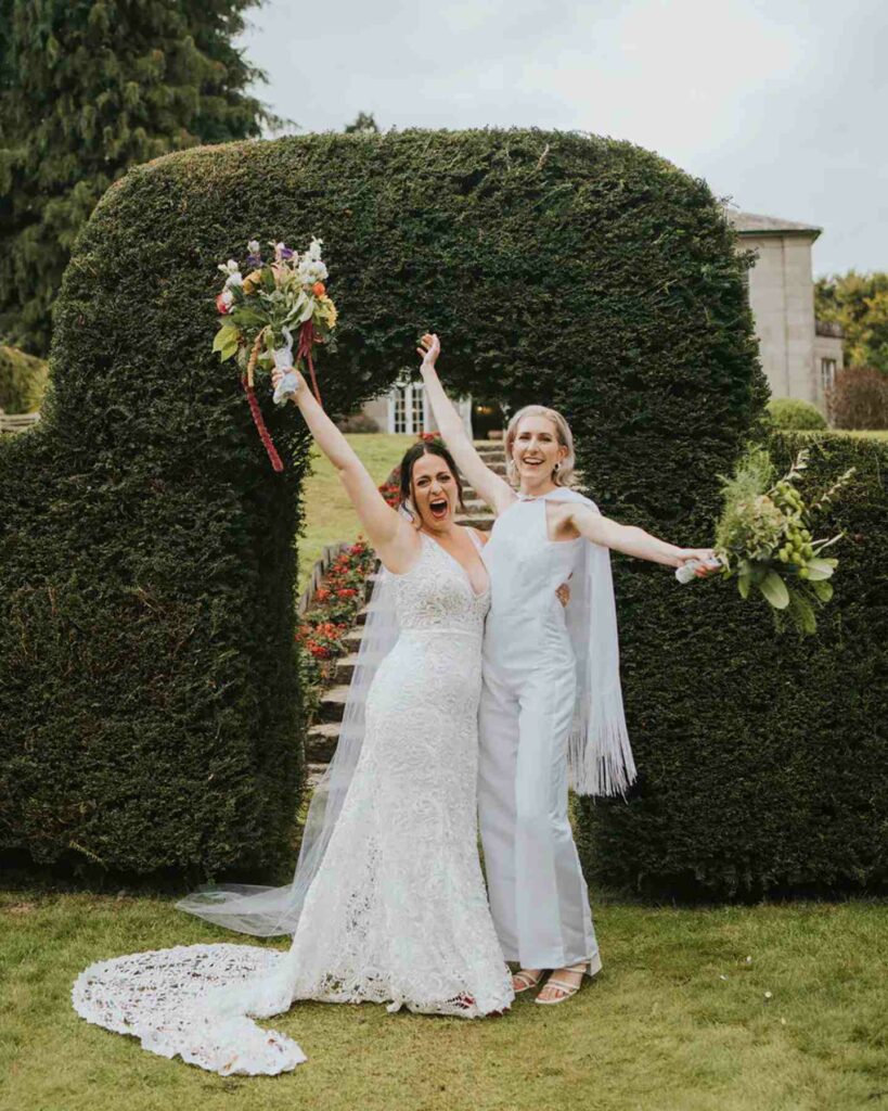 lesbian wedding brides in lace wedding dress and jumpsuit with colorful bouquet