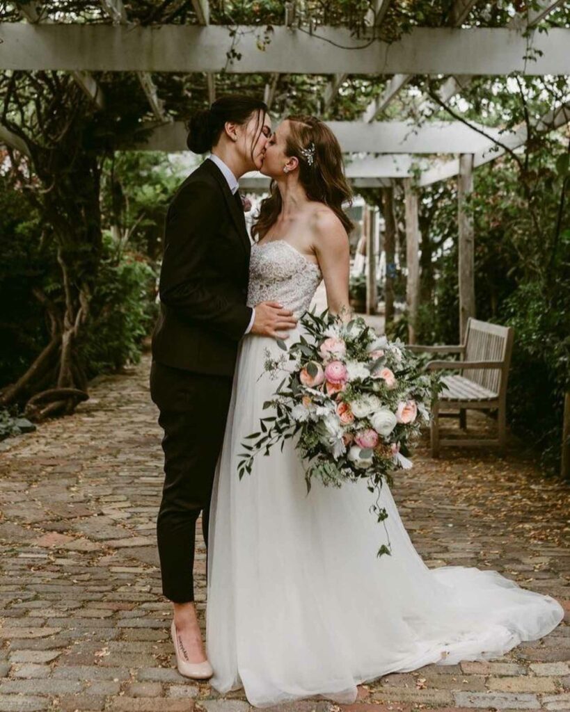 lesbian wedding in black suit and sexy white gown with blush bouquet