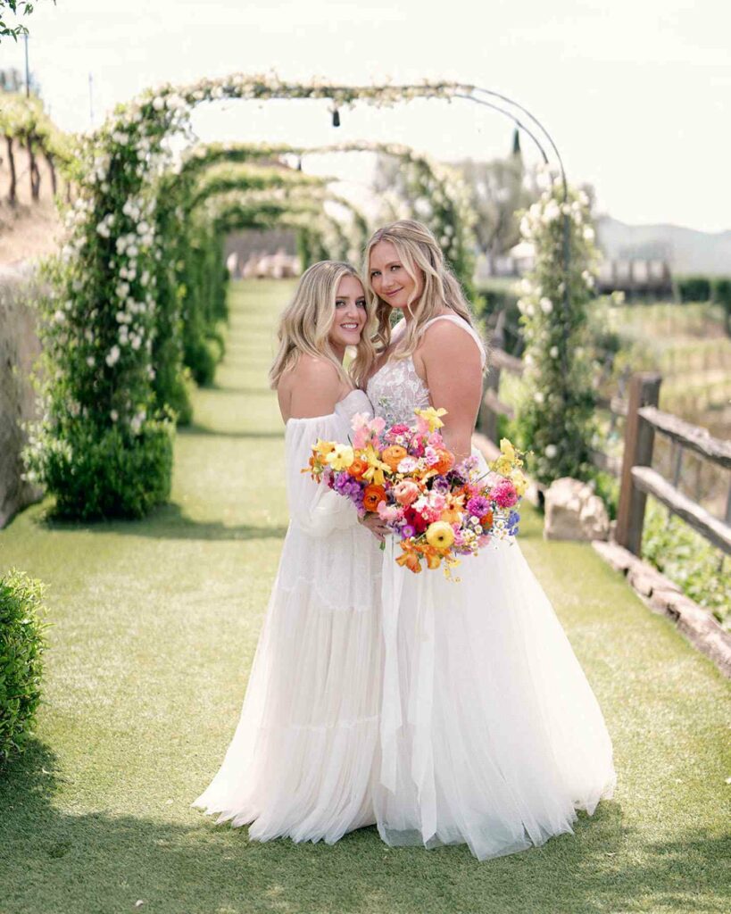pretty lesbian lace wedding outfits with rainbow themed bouquet