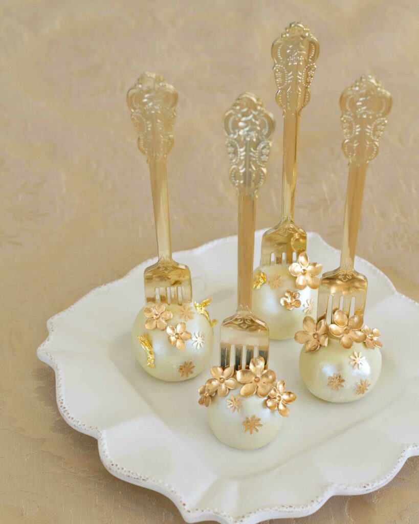 Wedding cake pops adorned with white and gold flowers