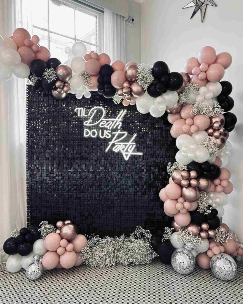 black photo booth backdrop with balloons and neon sign