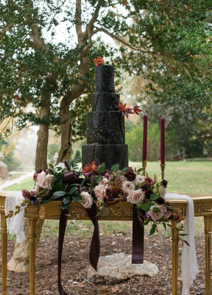 gothic four tiered wedding cake with floral arrangement