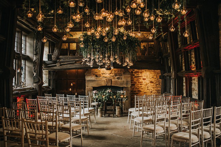 an intimate and rustic Christmas wedding ceremony setup featuring suspended greenery and twinkling lights