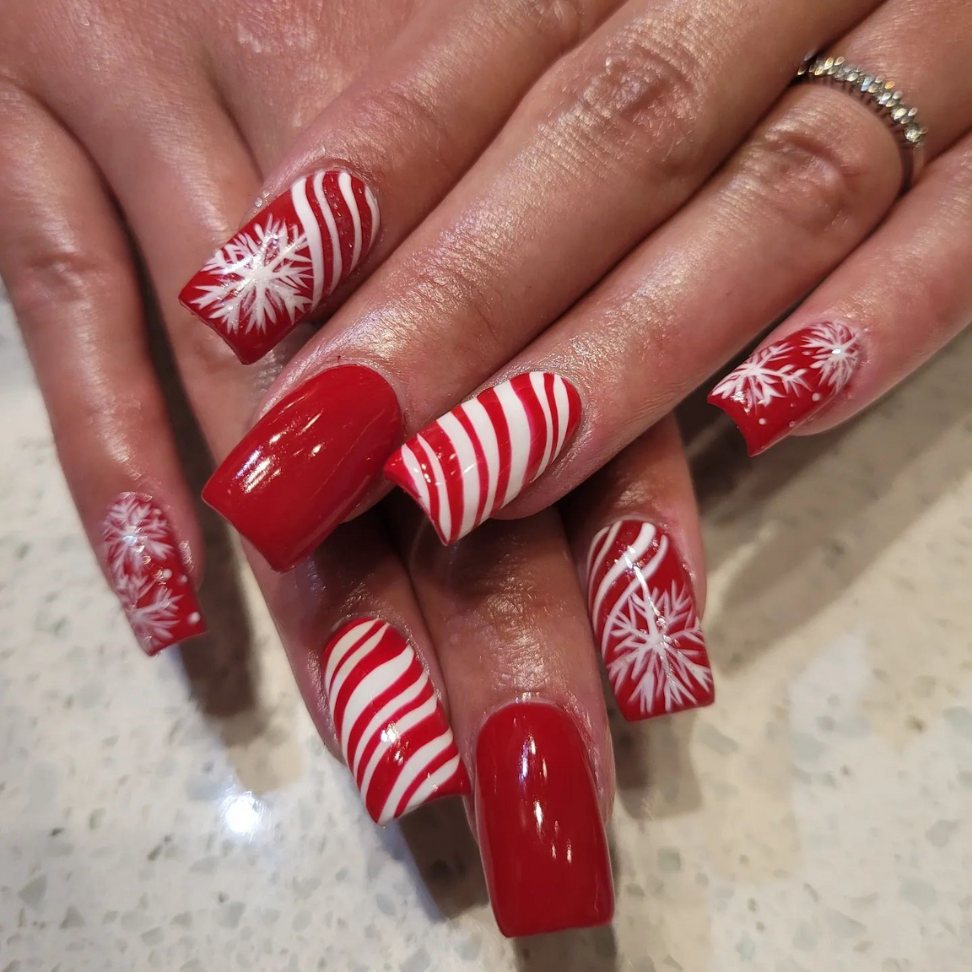bold red nails with white candy cane stripes and delicate snowflakes Christmas nails ideas