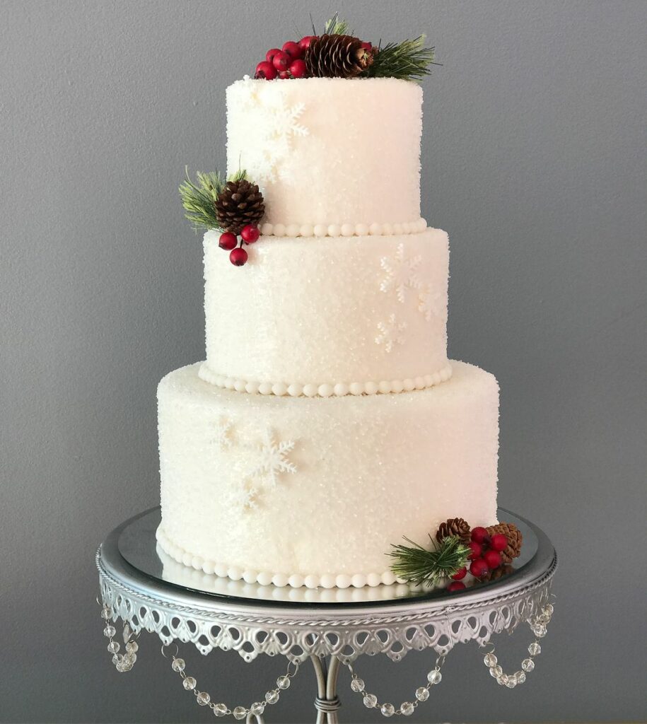 three tiered winter wedding cake with sprinkling sugar pinecones and snowflakes