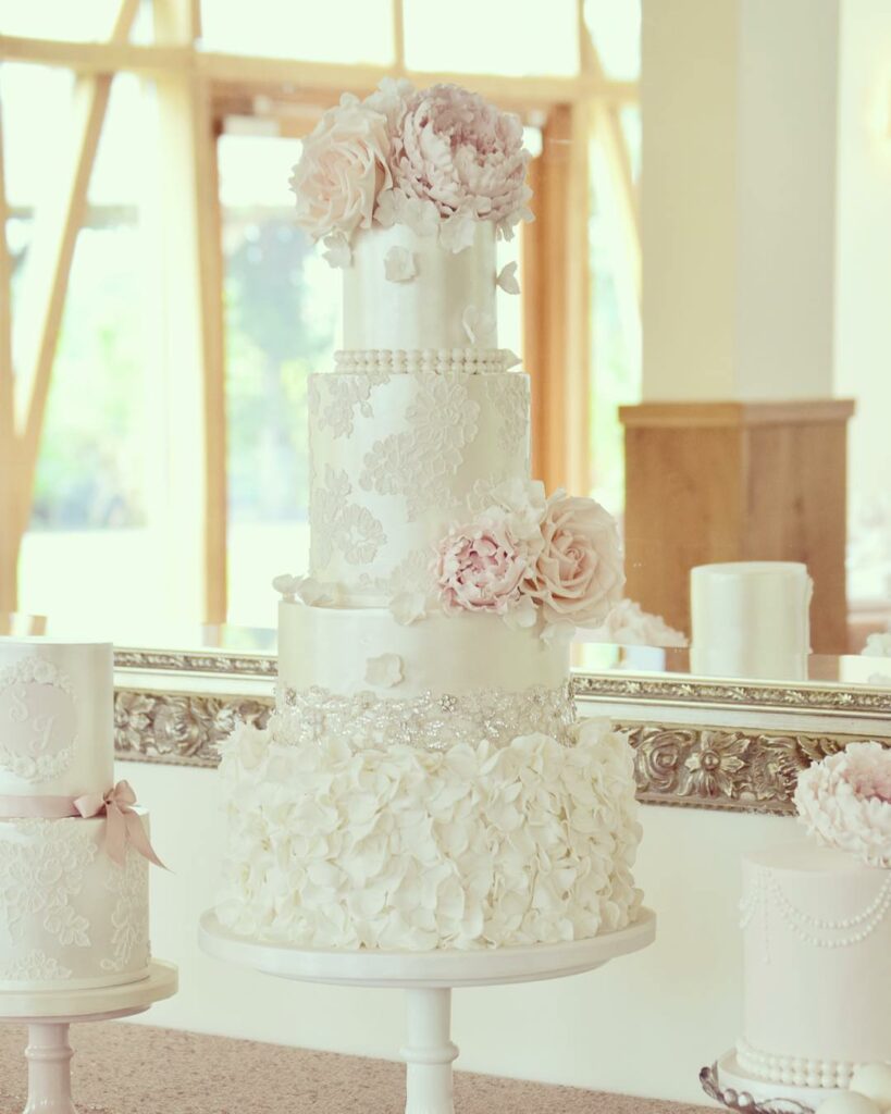 pearl and lace wedding cake with soft blooms