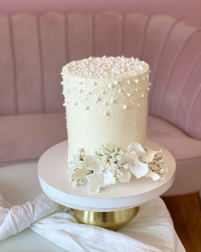pearl perfection wedding cake topped with a cascade of white blooms