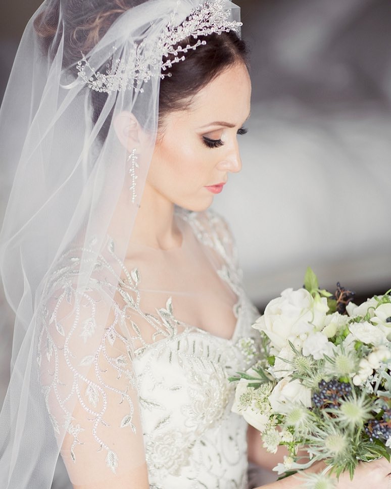 beautiful updo with gentle tendrils framing the face complementing her veil and tiaras intricate embellishments