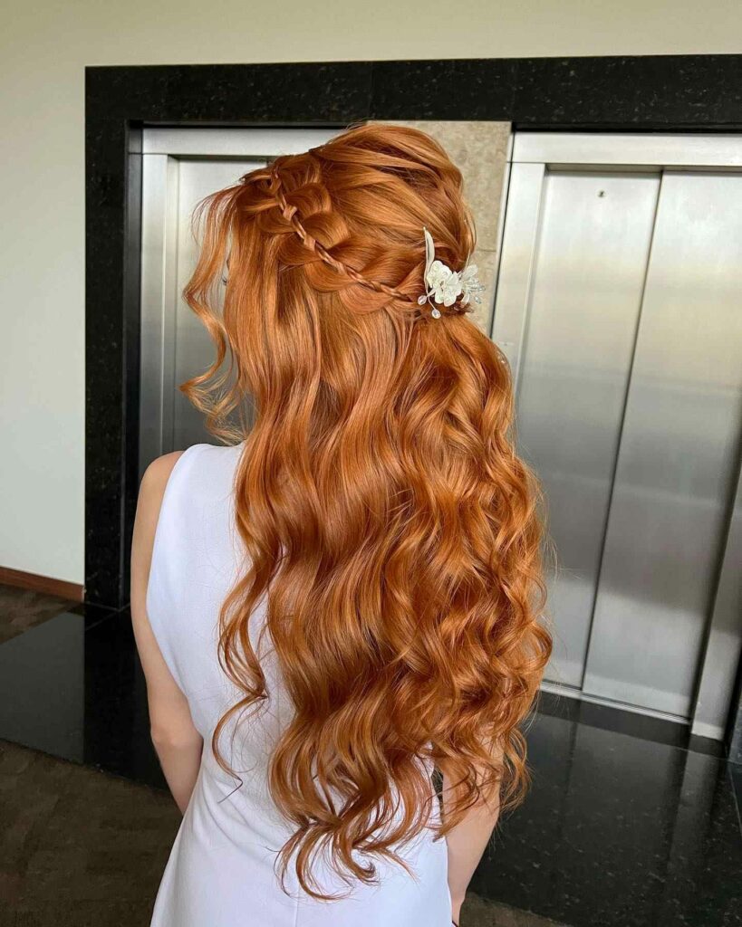 cascade of rich auburn curl and pulled into and half up braid with delicate floral hair piece