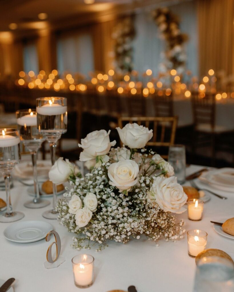 Elegant white roses, delicate baby's breath and warm votive candles create an intimate and romantic scene