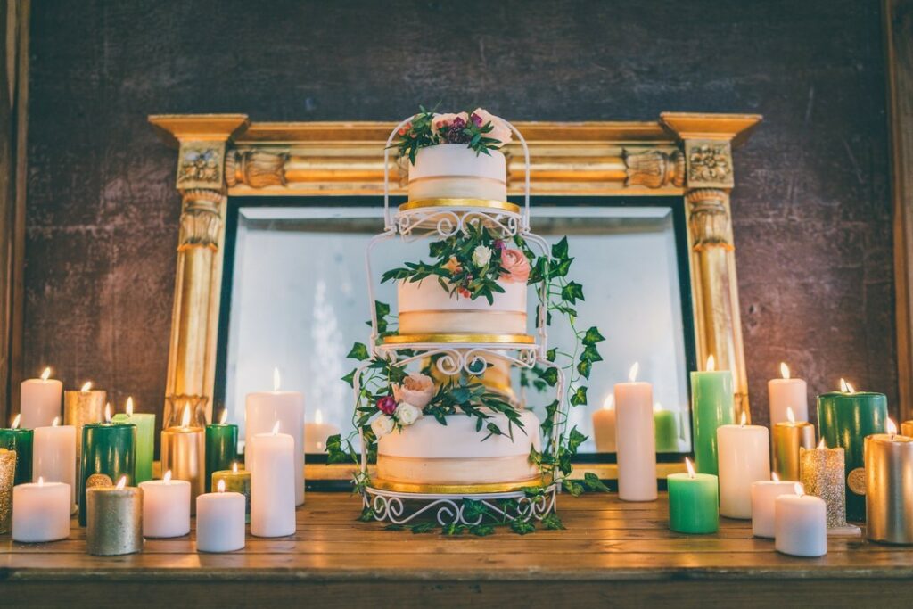green and gold three tiered wedding cake with candles