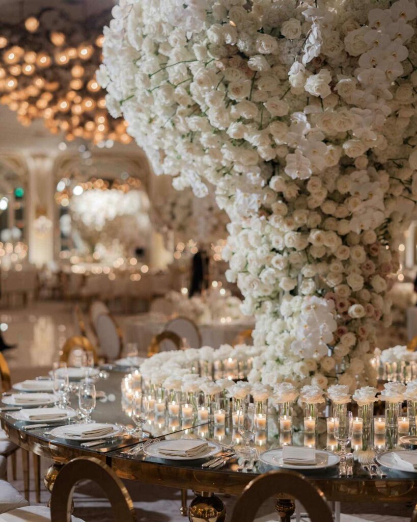 lavish wedding reception setting with floral centerpiece of cascading white orchids and roses with votive candles