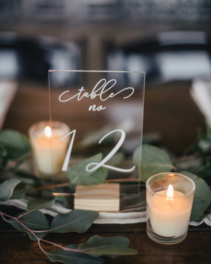 simple and chic wedding centerpiece with votive candles and acrylic table number