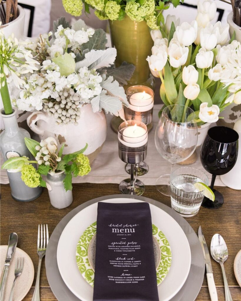 wedding table centerpiece with a blend of green and white floral arrangements and soft glow of tealight candles