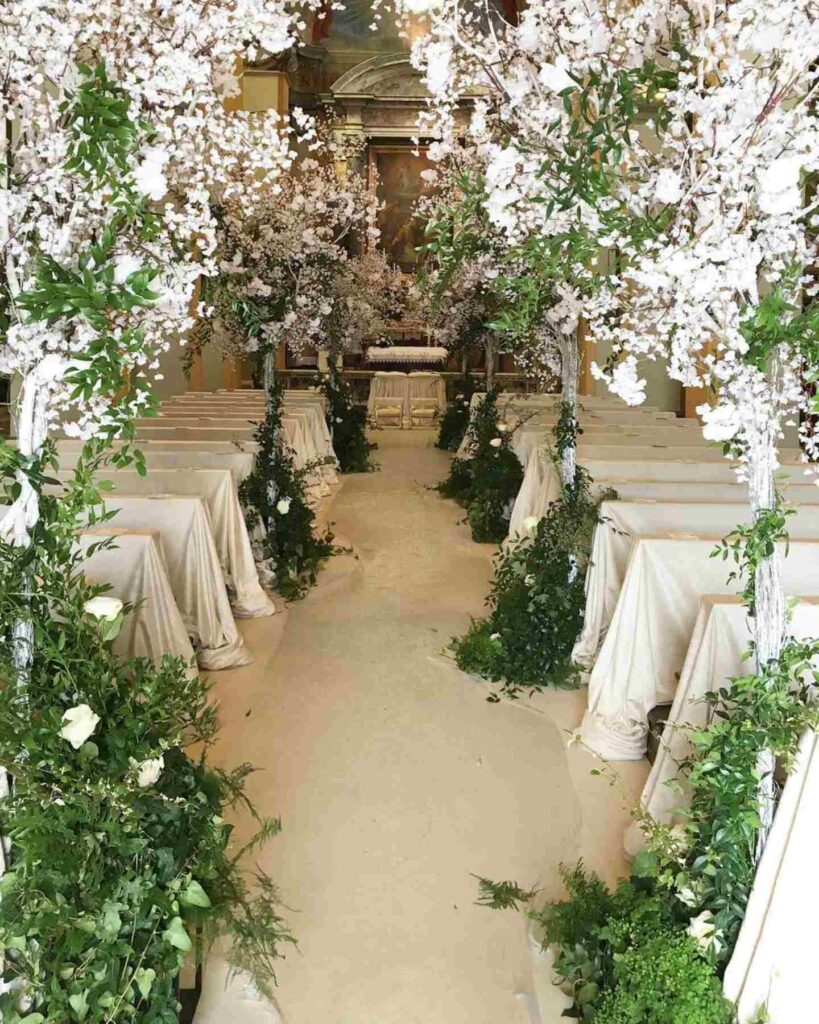 church wedding aisle adorned with lush greenery and white blossom